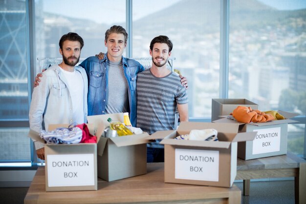 retrato-sonriente-equipo-negocios-creativos-pie-caja-donaciones-oficina_107420-98280